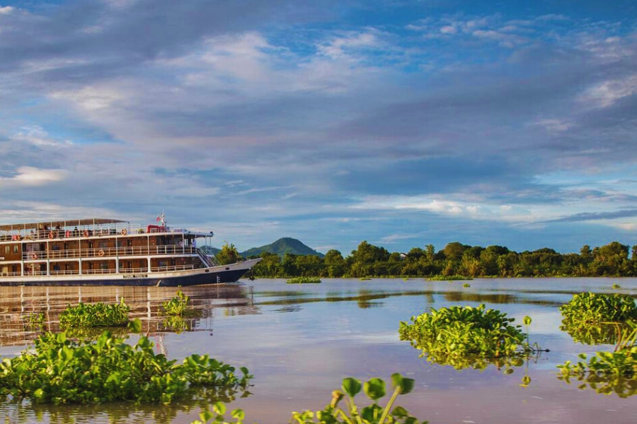 Serene Mekong River Cruise sailing at sunrise with lush greenery views by Auasia Travel